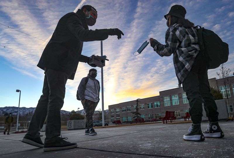 Salt Lake City School District board member Mohamed Baayd, right, greets students and hands out masks as they arrive at
East High School in Salt Lake City for their first day of in-person
learning in almost a year on Monday, Feb. 8, 2021.