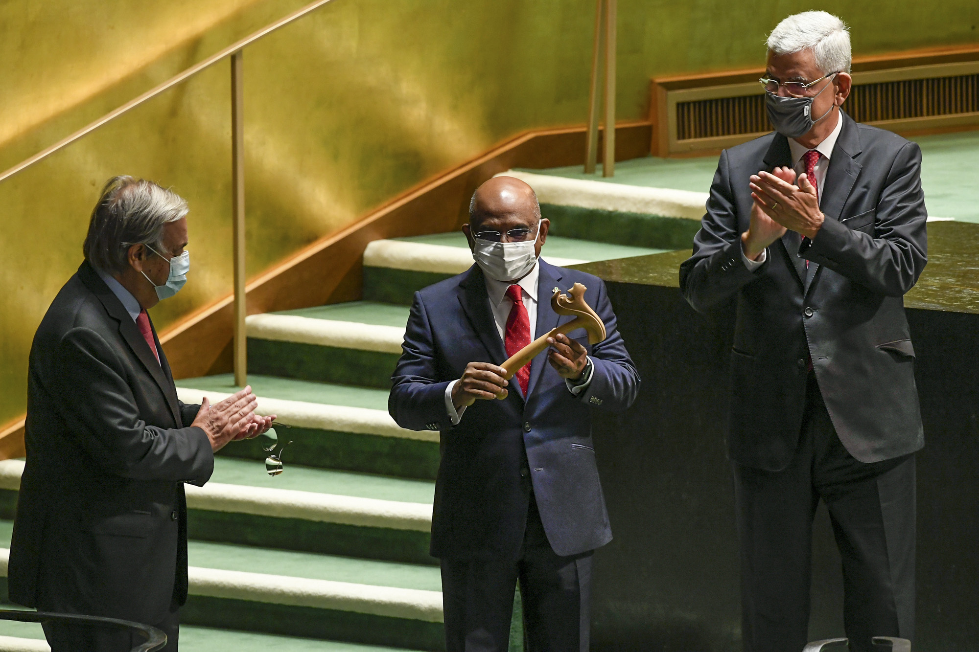 U.N. Secretary-General António Guterres, left, and Volkan Bozkir, right, president of the 75th session of the United Nations General Assembly, applaud as Abdulla Shahid, center, receives the gavel as the new president of the 76th session of the UNGA at U.N. headquarters.
