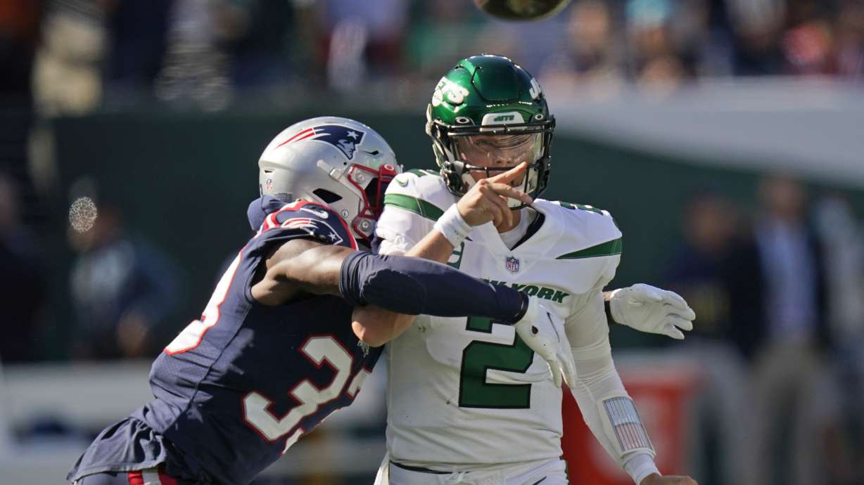 New York Jets quarterback Zach Wilson, right, throws under pressure from New England Patriots' Joejuan Williams during the second half of an NFL football game, Sunday, Sept. 19, 2021, in East Rutherford, N.J.