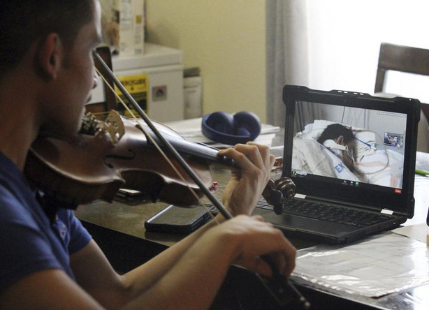 In this Jan. 27 photo, Emilian Sosa, 14, plays the violin for his mother seen on a computer screen at her hospital bed in McAllen, Texas.