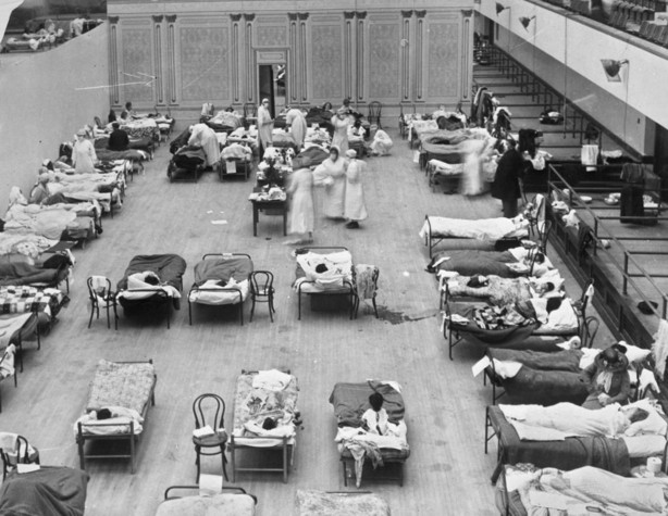 In this 1918 photo made available by the Library of Congress, volunteer nurses from the American Red Cross tend to influenza patients in the Oakland Municipal Auditorium, used as a temporary hospital.