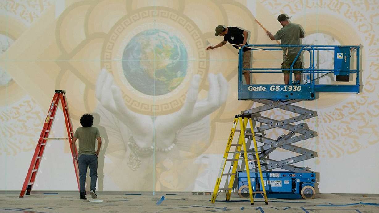 Alan Ochoa, left, Luis Novoa, center, and Miguel Galaz of the Roots Art Kollective paint a mural for UMFA's new exhibit.