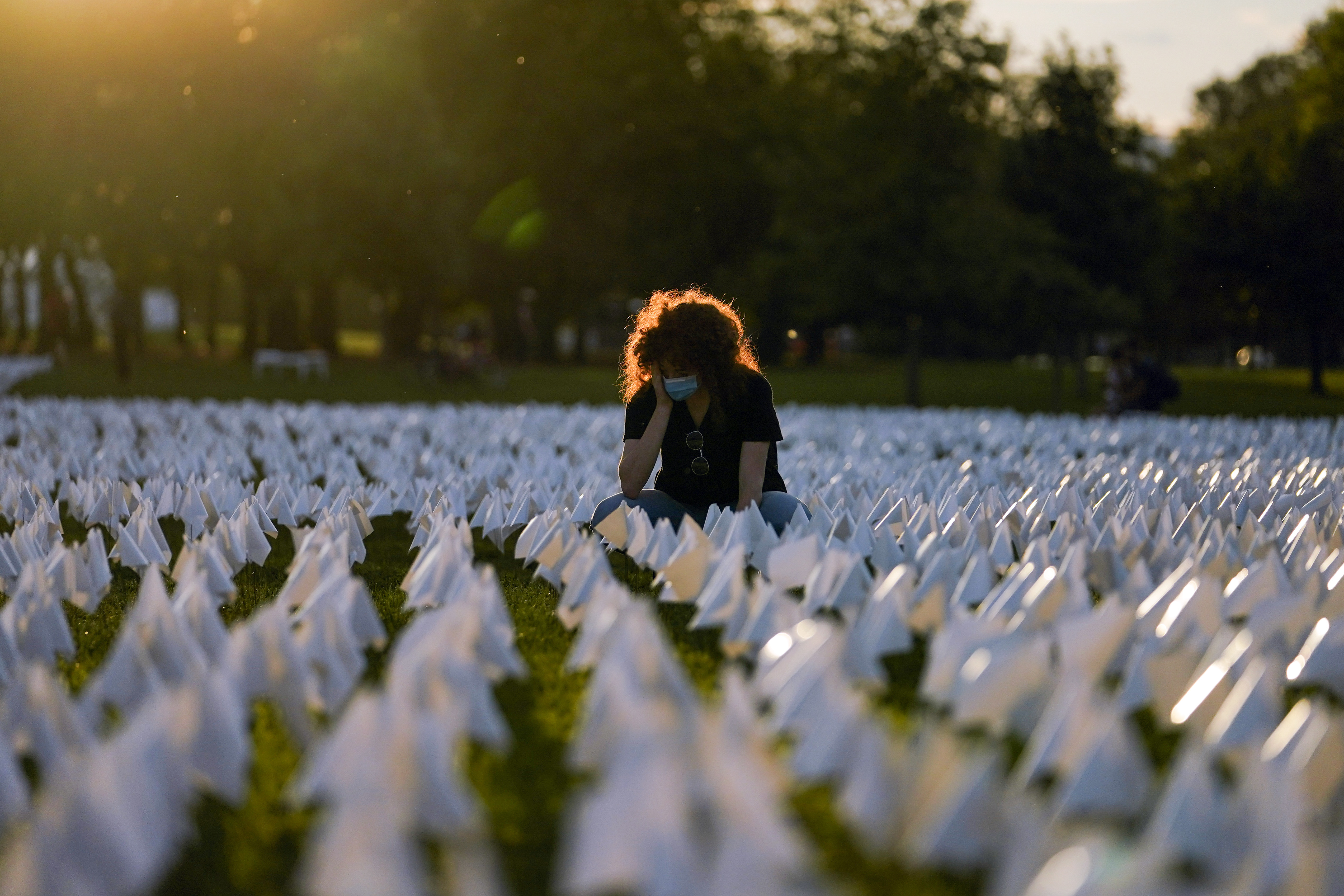 Zoe Nassimoff, of Argentina, looks at white flags that are part of artist Suzanne Brennan Firstenberg's temporary art installation, "In America: Remember," in remembrance of Americans who have died of COVID-19, on the National Mall in Washington, D.C., on Sept. 17. Nassimoff's grandparent who lived in Florida died from COVID-19.