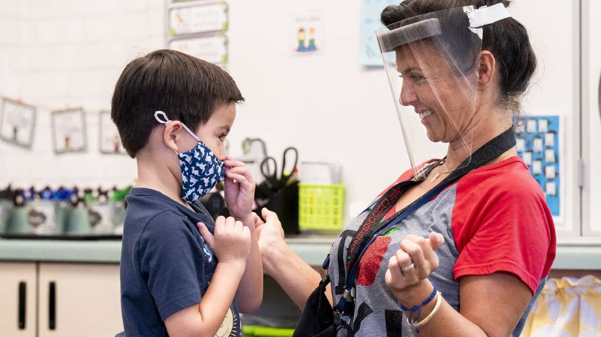 A student gets help with his mask from transitional kindergarten teacher Annette Cuccarese during the first day of classes at Tustin Ranch Elementary School in Tustin, California, on Aug. 12.