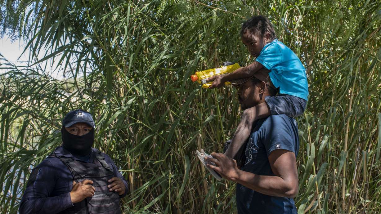 A Haitian migrant talks with a Mexican police officer blocking access to the Rio Grande river so that immigrants can't use it to cross the U.S.-Mexico border from Ciudad Acuna, Mexico, on Sept. 23.