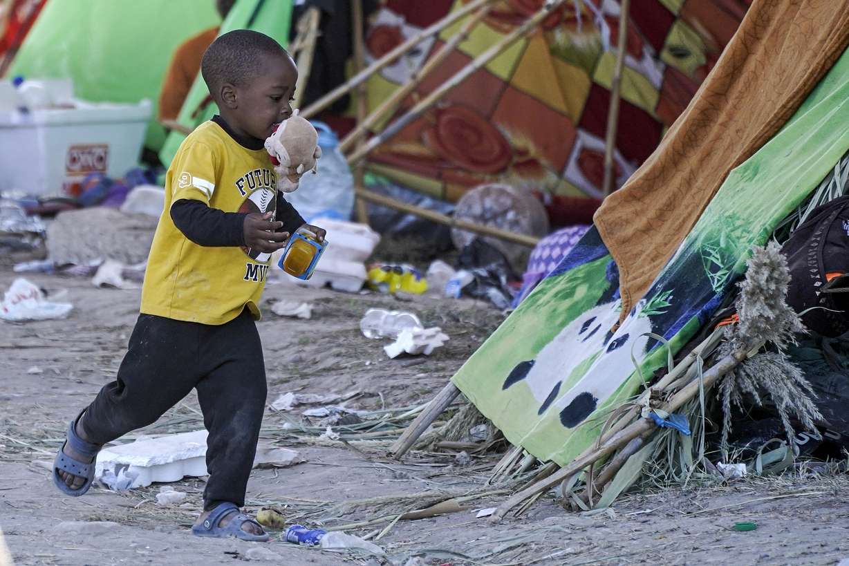 A migrant child runs with food he received from volunteers at an encampment under the Del Rio International Bridge where migrants, many from Haiti, have been staying after crossing the Rio Grande, Thursday, in Del Rio, Texas.