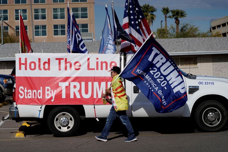 A protester carries a "Trump 2020" flag as Arizona electors gather to cast their votes at the Arizona Capitol, in Phoenix, Arizona, Dec. 14, 2020. A partisan review of the 2020 presidential election commissioned by Arizona Republicans has confirmed President Joe Biden's victory over Donald Trump.