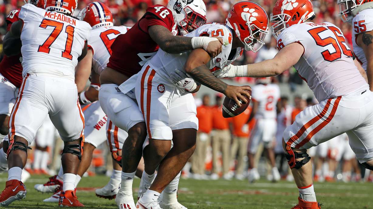 North Carolina State's Cory Durden (48) grabs a hold of Clemson's D.J. Uiagalelei (5) for a sack during the first half of an NCAA college football game in Raleigh, N.C., Saturday, Sept. 25, 2021.