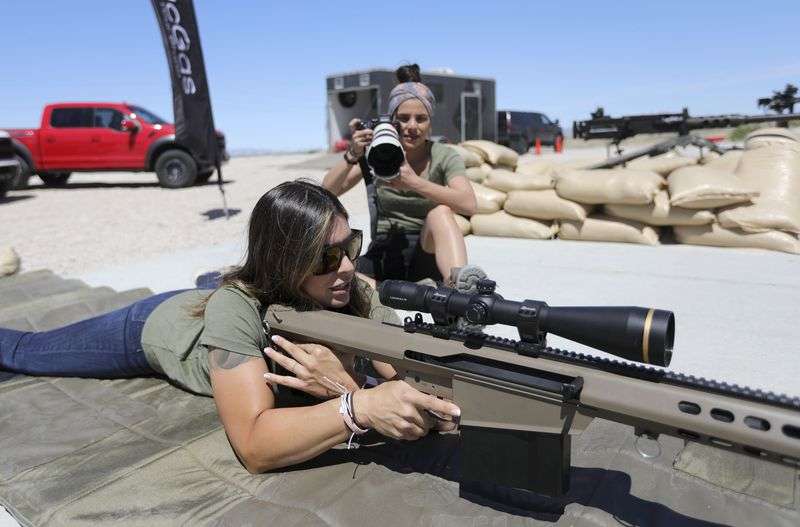 Professional shooter Michelle Viscusi poses with a Barrett M82A1 as TacGas photographer Alesha Bush photographs her during a photo shoot for a TacGas client at Special Weapons Test
Center near Grantsville on May 12.