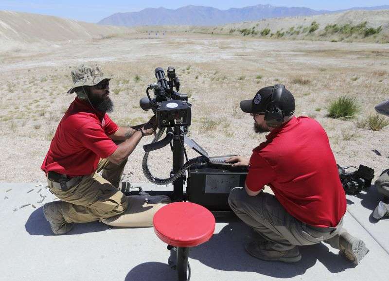 Special Weapons Test Center range safety officers Everett Williams and Kade Rogers prepare a mini gun, which uses 762 x 51 mm bullets, during a promotional video shoot for a TacGas
client at Special Weapons Test Center near Grantsville on May 12.