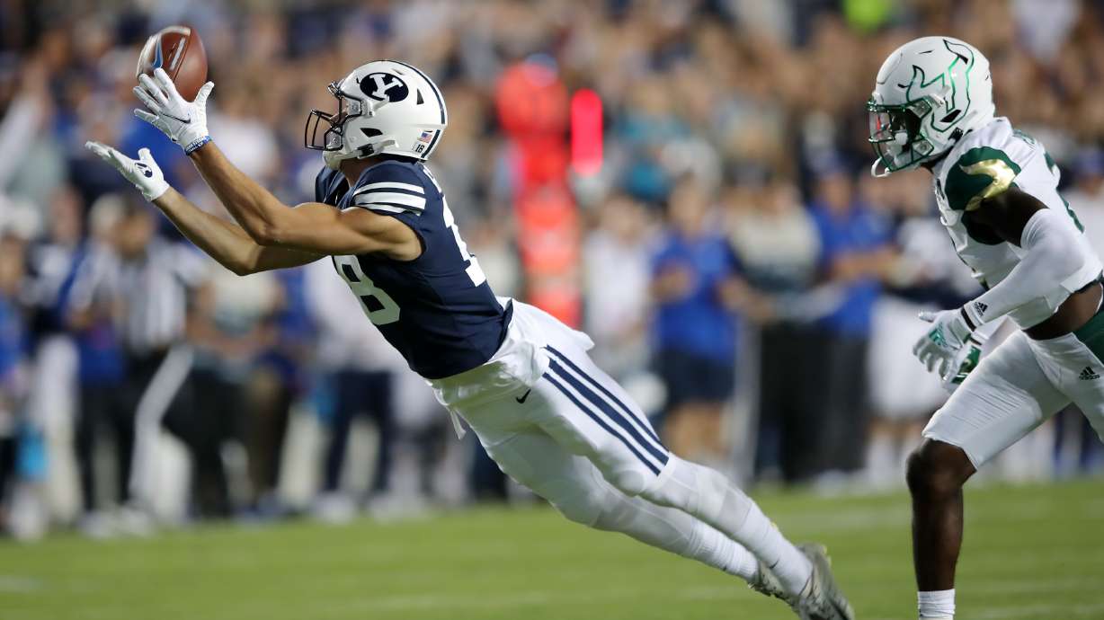 Brigham Young Cougars wide receiver Gunner Romney (18) stretches out for a long pass reception ahead of South Florida Bulls defensive back TJ Robinson (2) as BYU and USF play a college football game at LaVell Edwards Stadium in Provo on Saturday, Sept. 25, 2021.