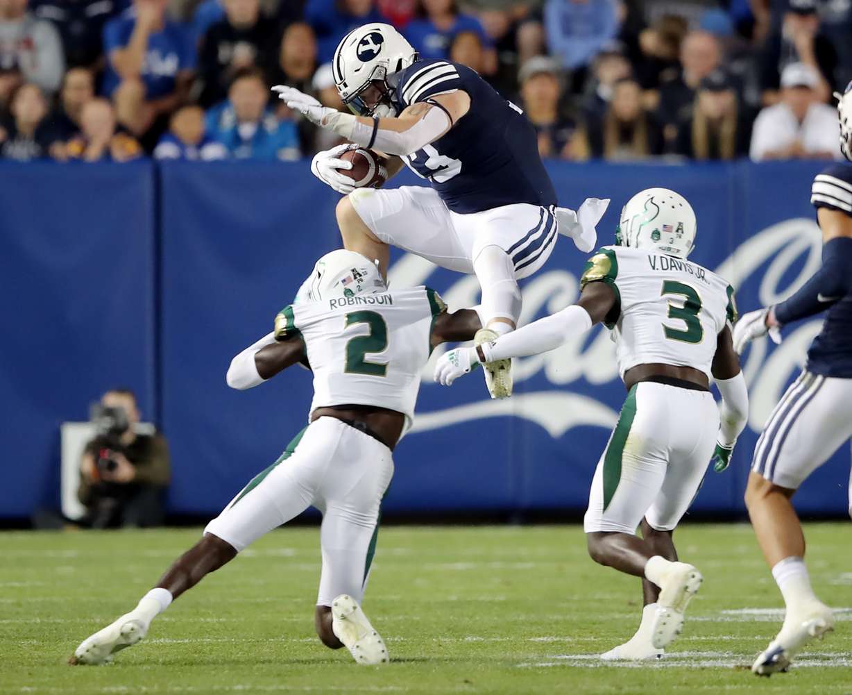 BYU fullback Masen Wake (13) tries to hurdle South Florida Bulls defensive back TJ Robinson (2) on a run as BYU and USF play a college football game at LaVell Edwards Stadium in Provo on Saturday.