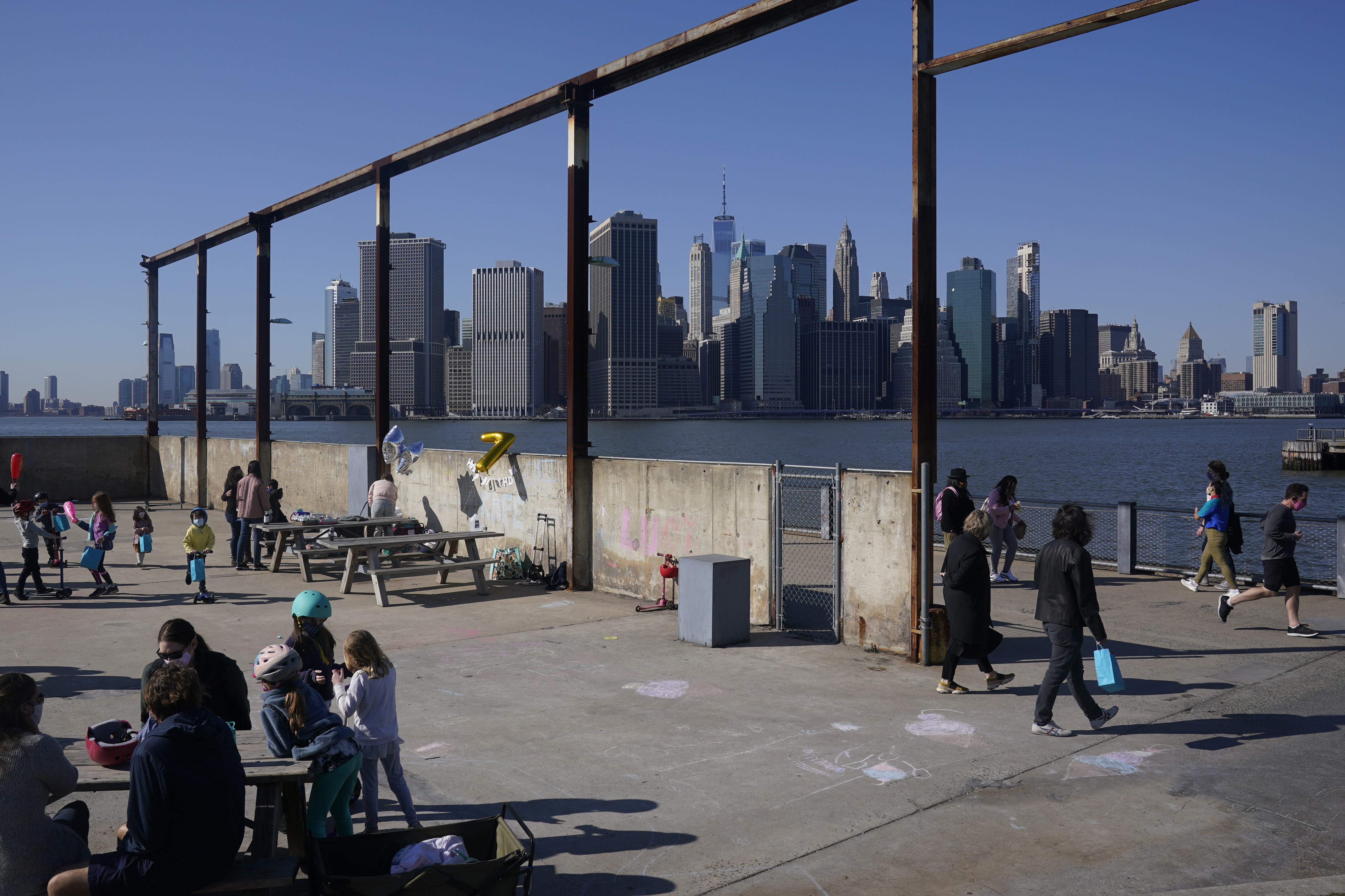 People enjoy the sunny weather and a view of the Manhattan skyline from the Brooklyn waterfront in New York. 
