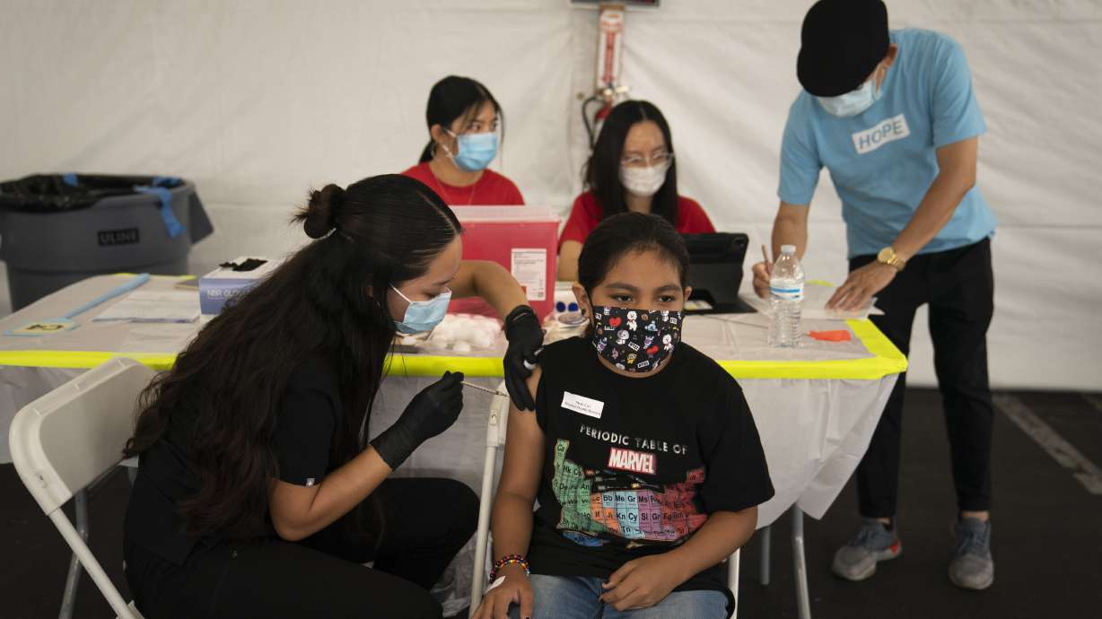 Mayra Navarrete, 13, receives the Pfizer COVID-19 vaccine from registered nurse, Noleen Nobleza at a clinic set up in the parking lot of CalOptima in Orange, Calif.