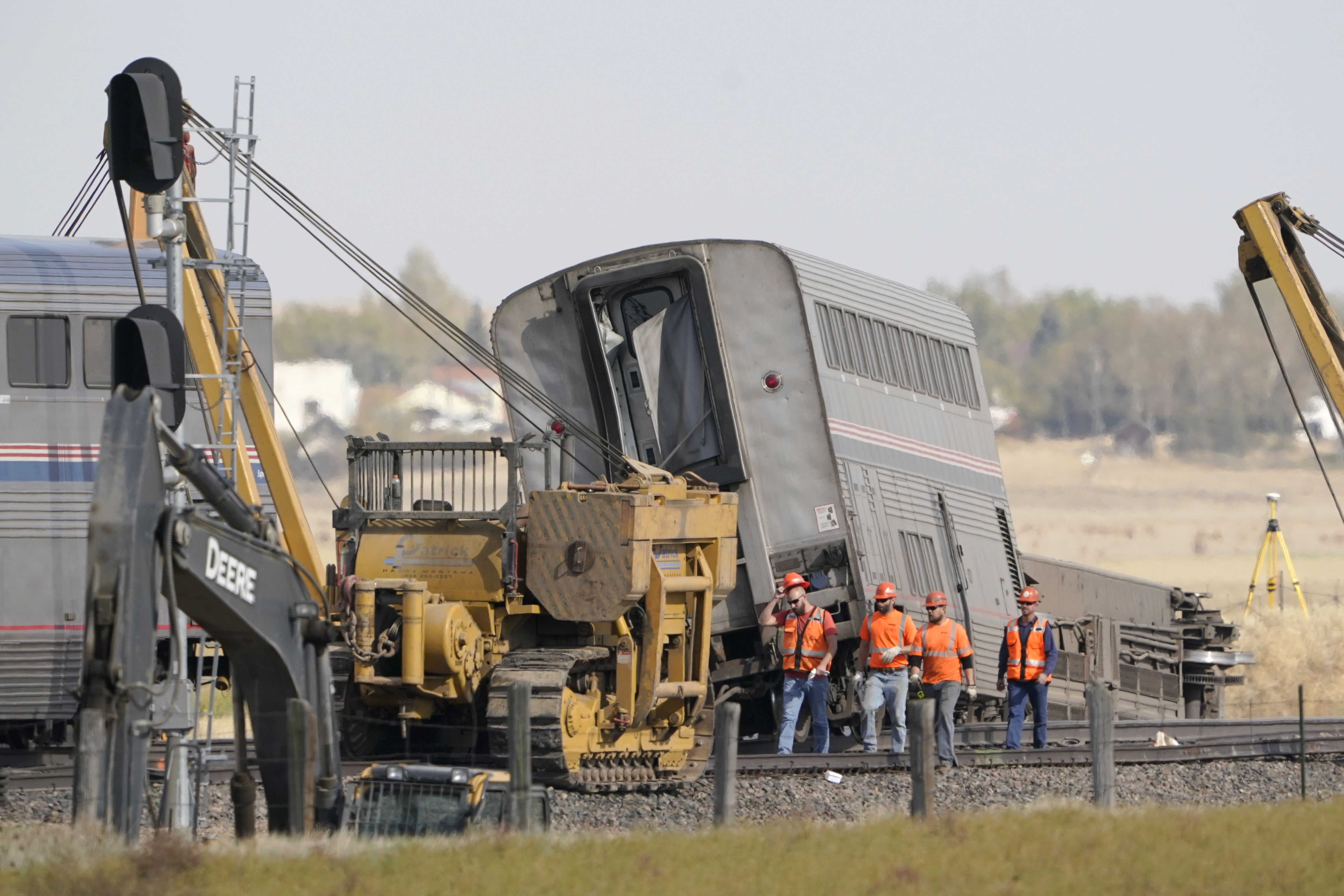 Workers walk Sunday next to an Amtrak train that derailed Saturday just west of Joplin, Mont.