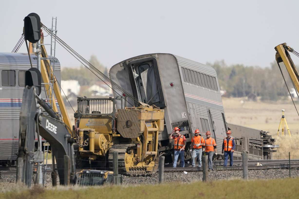 Workers walk Sunday next to an Amtrak train that derailed Saturday just west of Joplin, Mont.