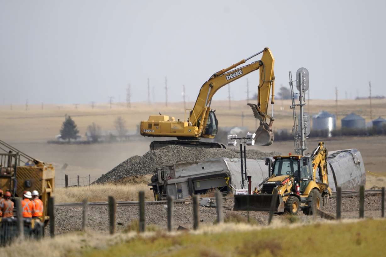 Heavy equipment moves gravel Sunday next to cars from an an Amtrak train that derailed Saturday just west of Joplin, Mont.