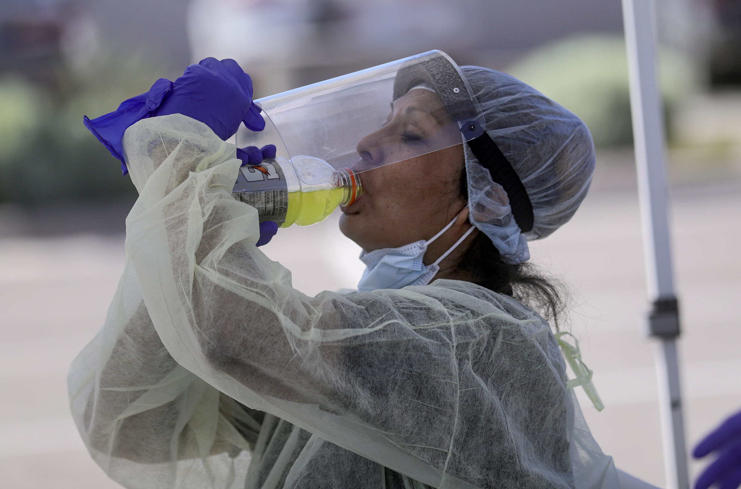 Bonnieva Bitsuie, Utah Navajo Health System contracted maintenance worker and housekeeper, lifts her face shield to take a sip of Gatorade while working with a mobile COVID-19 testing unit outside of the Montezuma Creek Community Health Center in Montezuma Creek, San Juan County, on May 1, 2020. Utah Navajo Health System is one of 11 Utah health centers to receive funding from the American Rescue Plan Act.