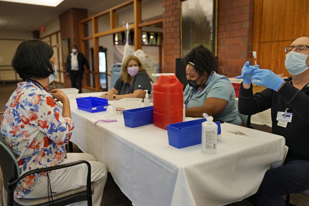 Cristina Licup, left, waits to receive her COVID-19 booster shot on Monday where she works at the Hebrew Home at Riverdale in New York. The number of COVID-19 vaccinations is falling in the U.S. And some experts worry that the decision to give booster doses could end up hurting efforts to get the unvaccinated to take shots at all.