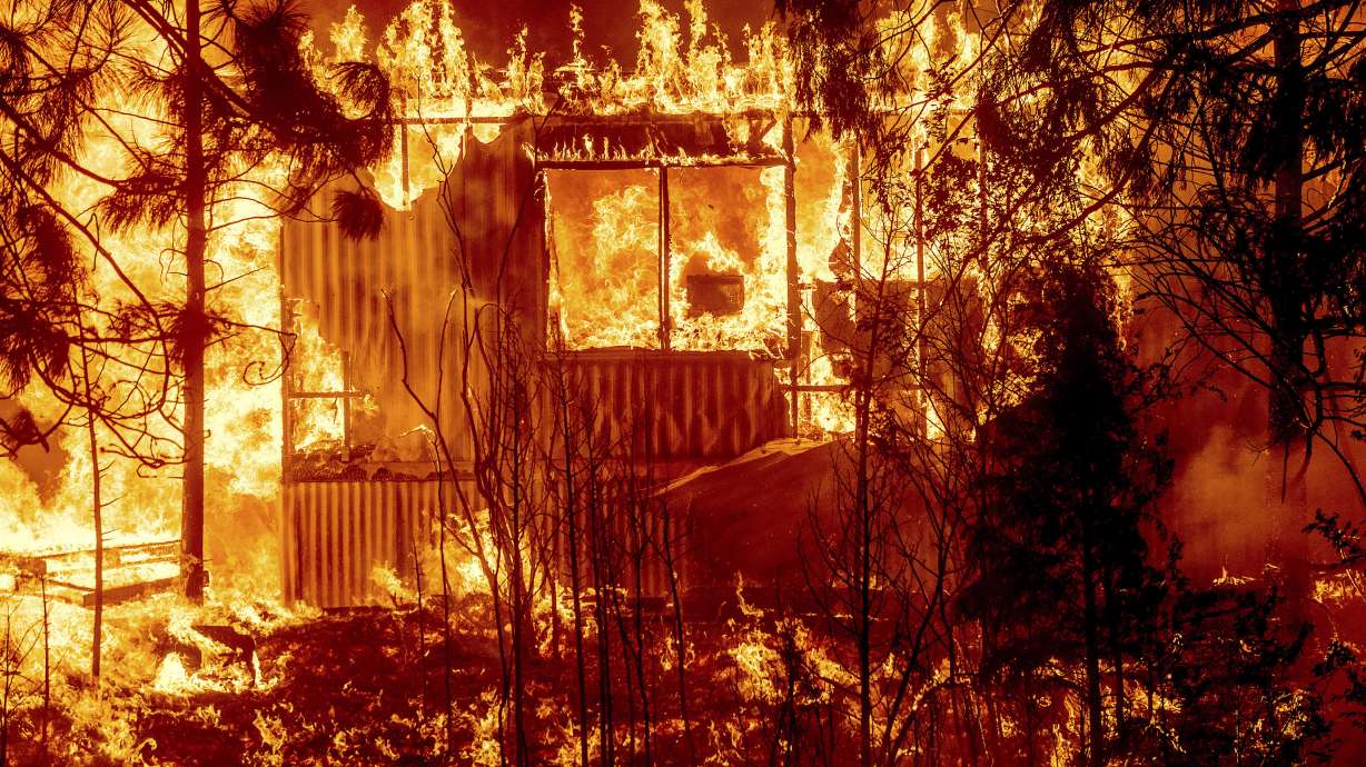 Flames consume a home surrounded by trees on Highway 89 as the Dixie Fire tears through the community of Greenville in Plumas County, Calif., Aug. 4, 2021. Pacific Gas & Electric power lines sparked last summer's Dixie Fire in Northern California that swept through five counties and burned more than 1,300 homes and other buildings, state fire officials said Tuesday, Jan. 4, 2022.