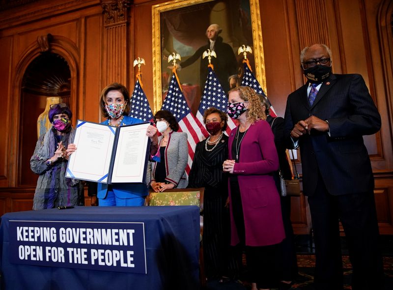U.S. House Speaker Nancy Pelosi, D-Calif., is flanked by members of the House Democratic Caucus as she holds the continuing resolution she signed to avoid a U.S. government shutdown during a bill enrollment ceremony on Capitol Hill in Washington, Wednesday.