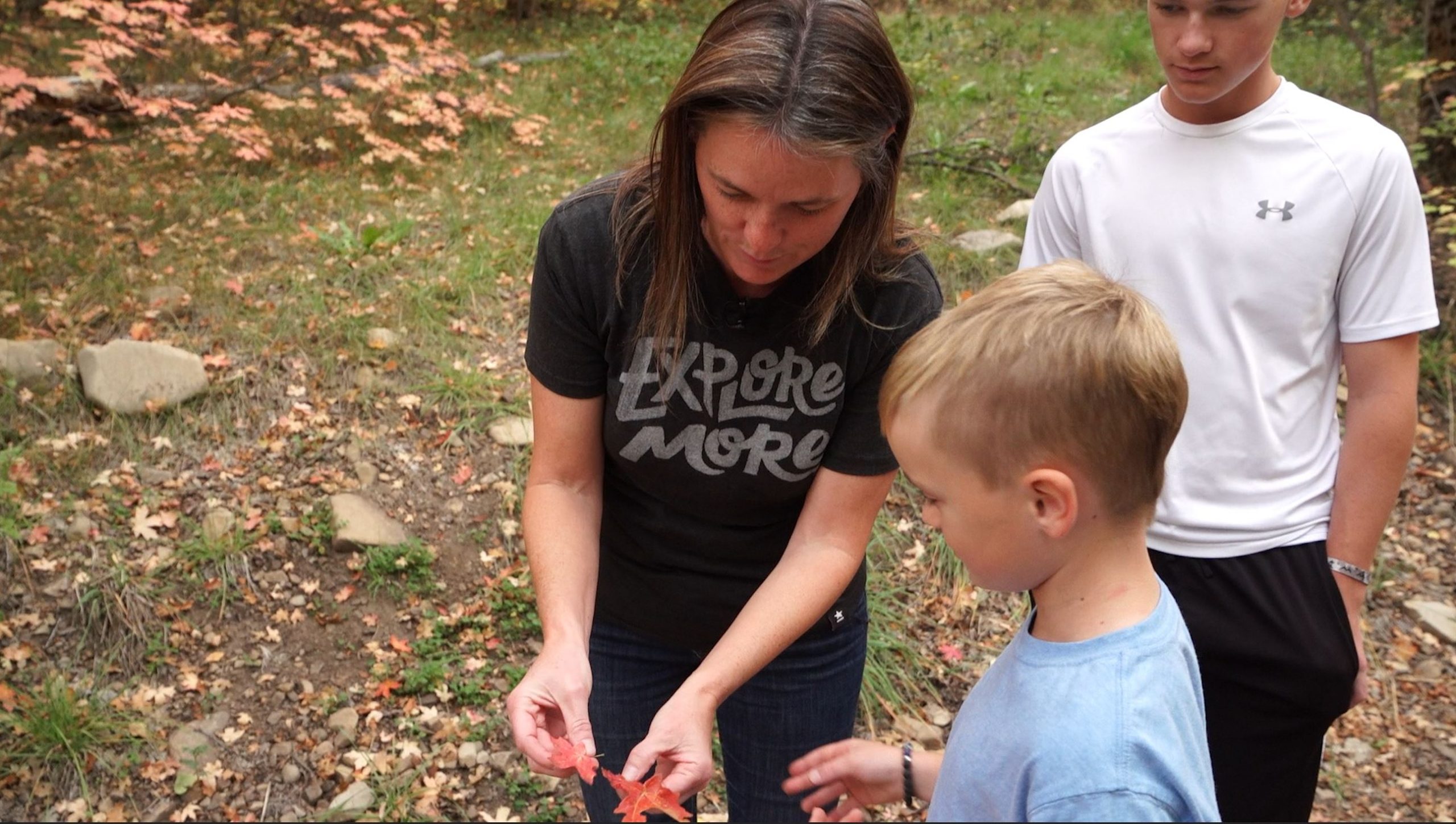 Natalie Ockey and two of her sons look at leaves on a hike.