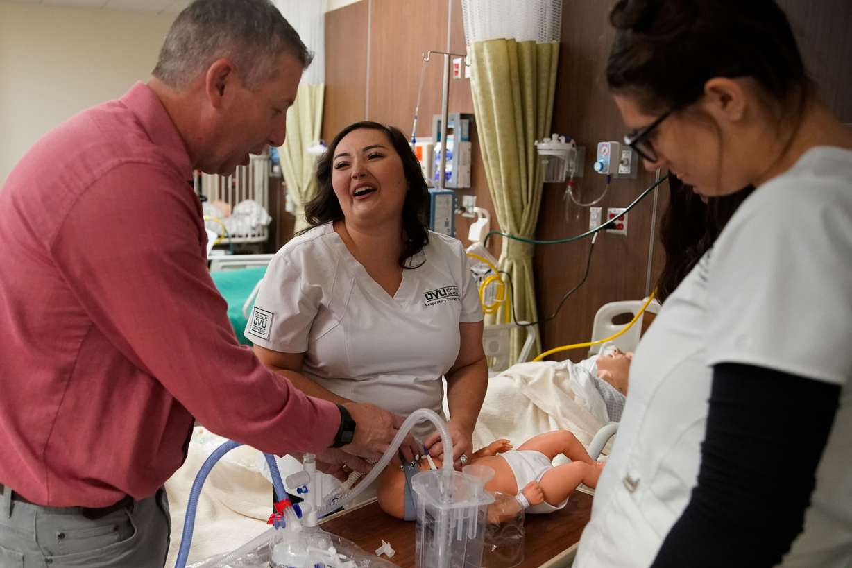 Dominique Elder, a student and respiratory therapist assistant at Utah Valley University, middle, laughs, as classmate Mica Alden, right, watches lab instructor Steve Panton demonstrate the steps of neonatal continuous positive airway pressure therapy on a mannequin during a lab at Utah Valley University in Orem on Thursday, Sept. 30, 2021.