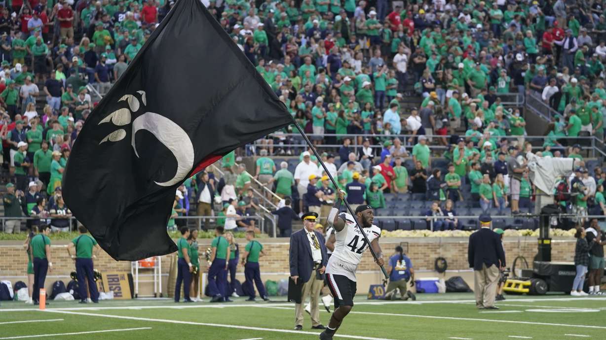 Cincinnati's Malik Vann (42) runs with the school's flag after Cincinnati defeated Notre Dame, 24-13, in an NCAA college football game, Saturday, Oct. 2, 2021, in South Bend, Ind.