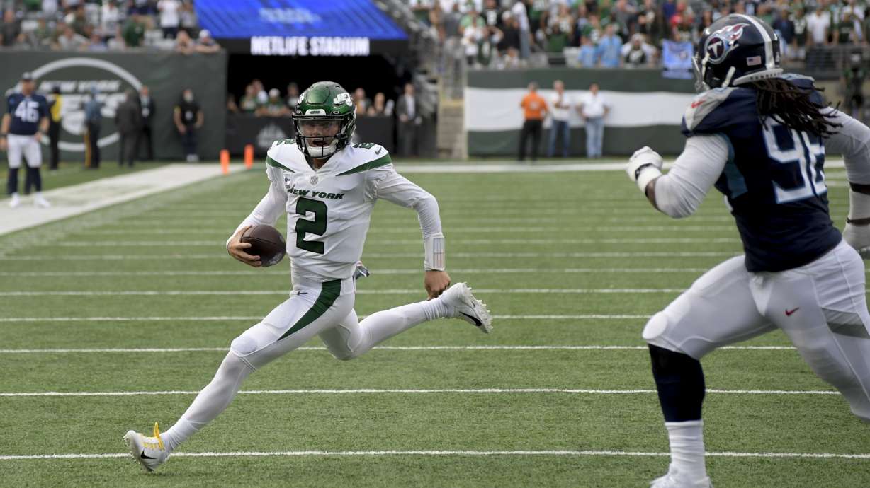 New York Jets quarterback Zach Wilson (2) runs the ball against Tennessee Titans defensive end Denico Autry (96) during overtime of an NFL football game, Sunday, Oct. 3, 2021, in East Rutherford, N.J.