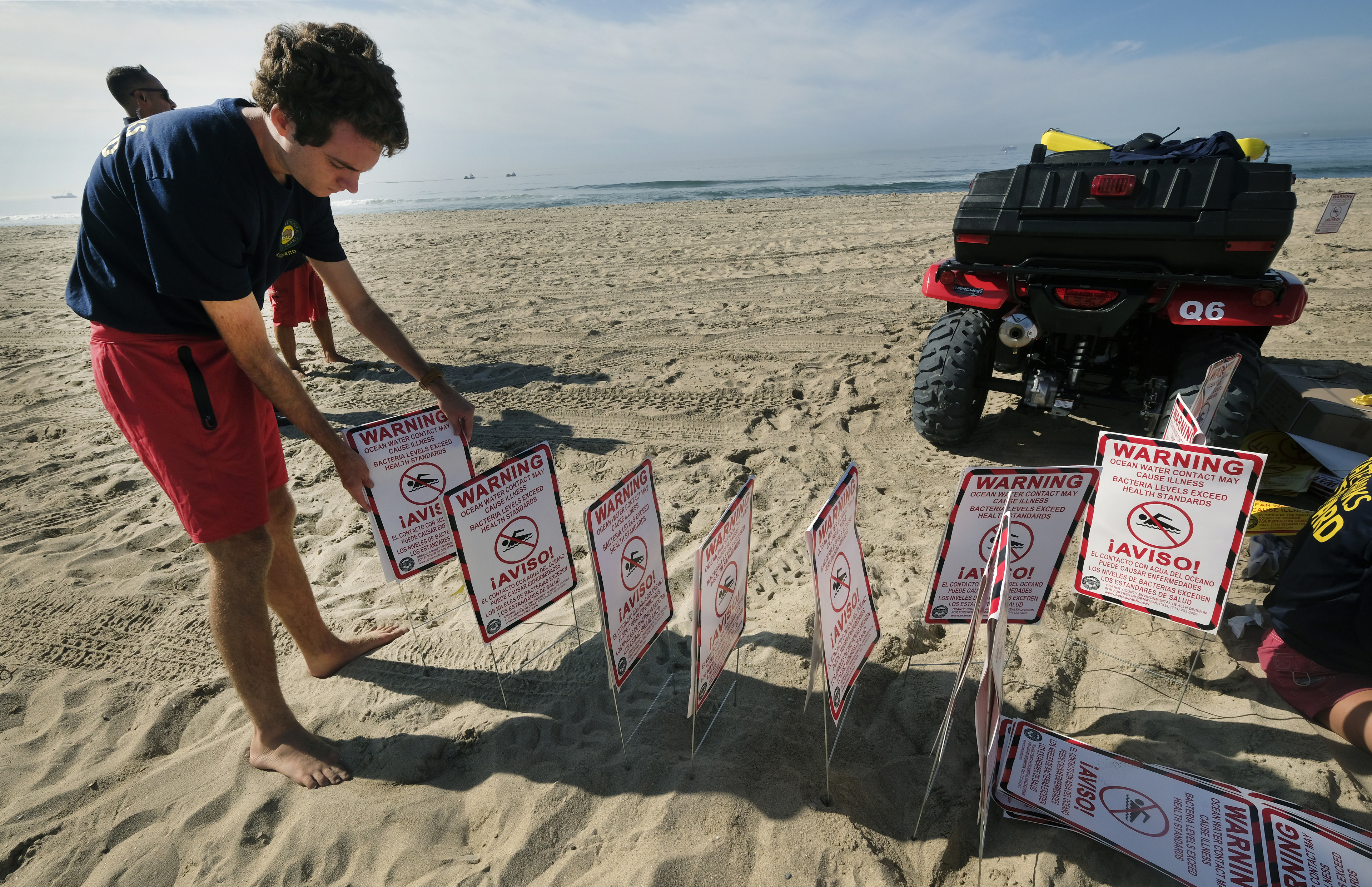 Lifeguards ready to post signs warning that water contact may cause illness, as they close the beach after an oil spill in Huntington Beach, California, Sunday. The closure stretched from the Huntington Beach Pier nearly four miles south to the Santa Ana River jetty amid summer-like weather that would have brought beachgoers to the wide strand for volleyball, swimming and surfing. Yellow caution tape was strung between lifeguard towers to keep people away. 