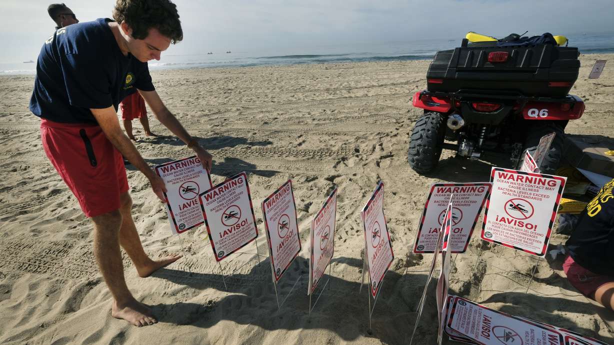 Lifeguards ready to post signs warning that water contact may cause illness, as they close the beach after an oil spill in Huntington Beach, California, Sunday. The closure stretched from the Huntington Beach Pier nearly four miles south to the Santa Ana River jetty amid summer-like weather that would have brought beachgoers to the wide strand for volleyball, swimming and surfing. Yellow caution tape was strung between lifeguard towers to keep people away.