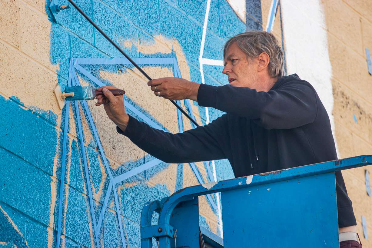 Utah artist Jimmi Toro paints his mural outside of the INDUSTRY business office in Salt Lake City Monday. His mural will be one of 10 across the county showcasing the Salt Lake County experience.