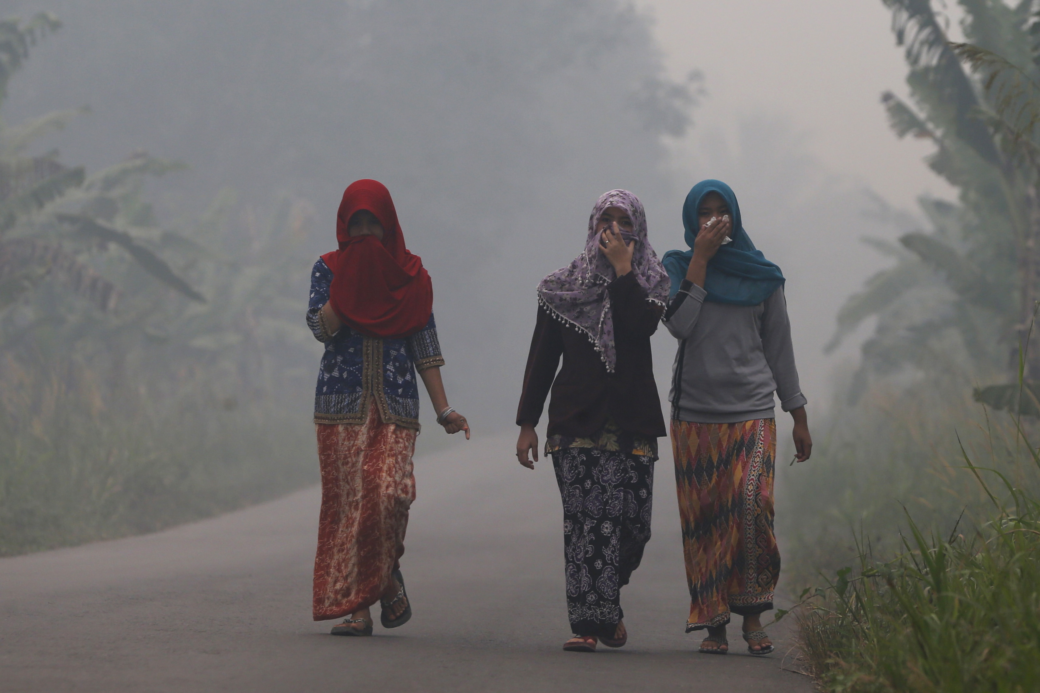 Villagers walk on a street as the haze shrouds Pulau Mentaro village in Muaro Jambi, on the Indonesian island of Sumatra, Sept. 15, 2015. Britain and the United States are among a few countries withholding support for a proposal brought at the United Nations that would recognize access to a safe and healthy environment as a human right.
