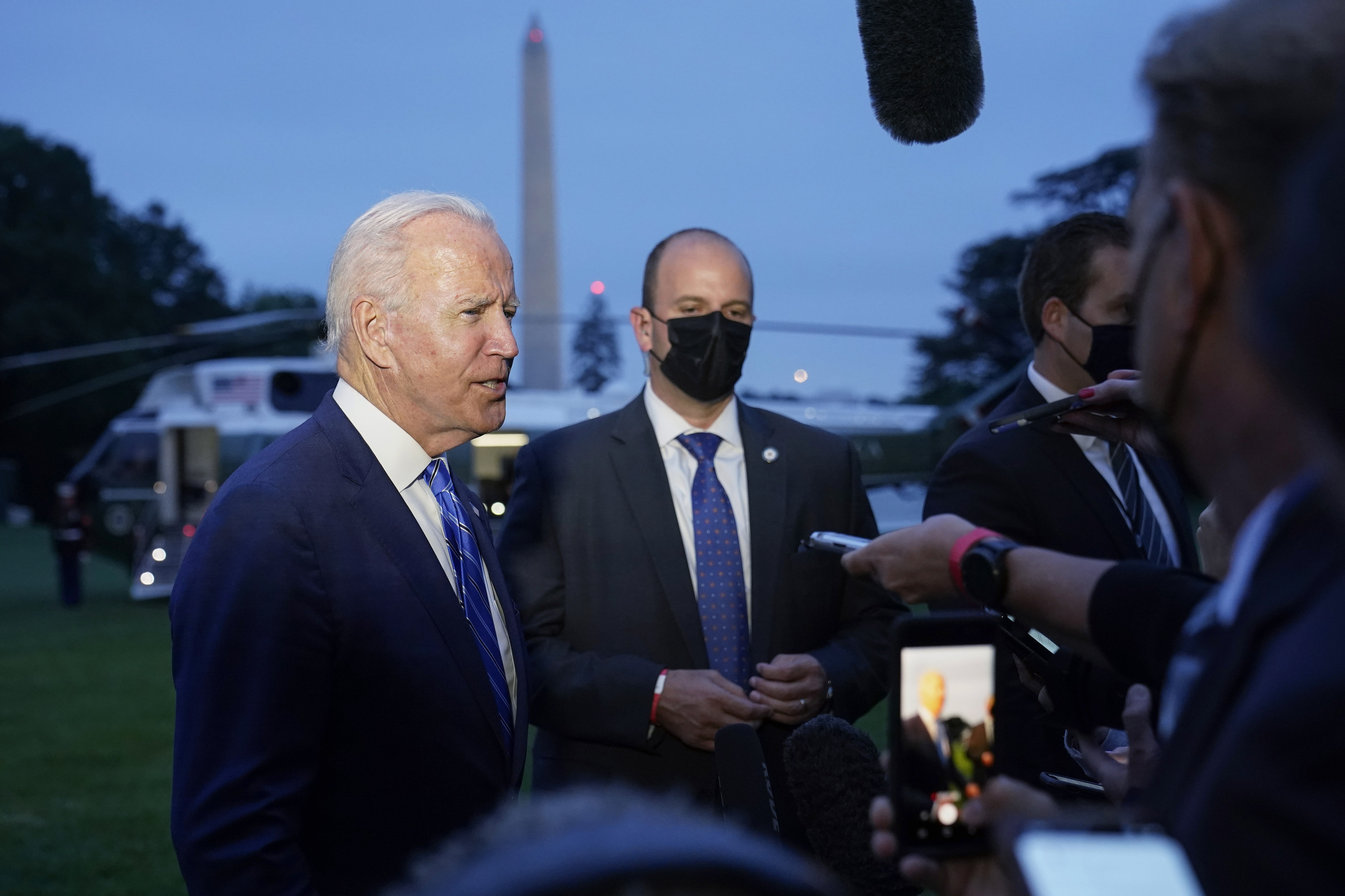 President Joe Biden talks with reporters after returning to the White House Tuesday after a trip to promote his infrastructure plan. The president is repeatedly conceding that the measure will be considerably smaller than $3.5 trillion.