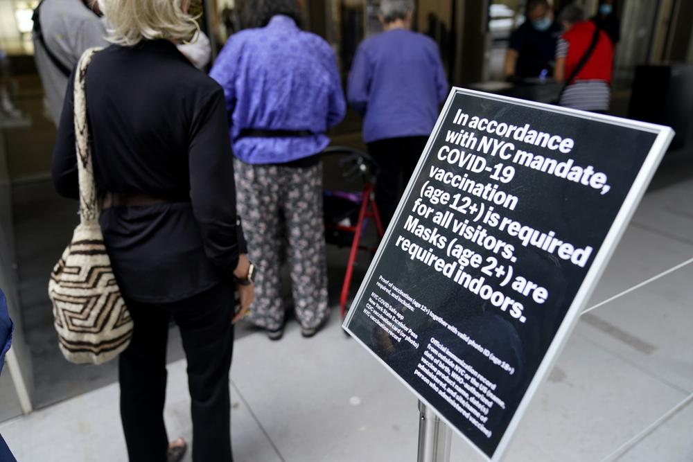 In this Sept. 13 photo, staff at the Modern Museum of Art check visitors' proof of vaccination in New York. COVID-19 deaths in the U.S. are coming down again, hospitalizations are dropping, and new cases per day are about to dip below 100,000 for the first time in two months — all signs that the summer surge is waning.