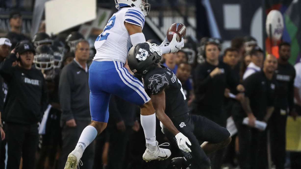 Brigham Young Cougars wide receiver Puka Nacua (12) grabs a pass over Utah State Aggies cornerback Cam Lampkin (6) in Logan on Friday, Oct. 1, 2021.