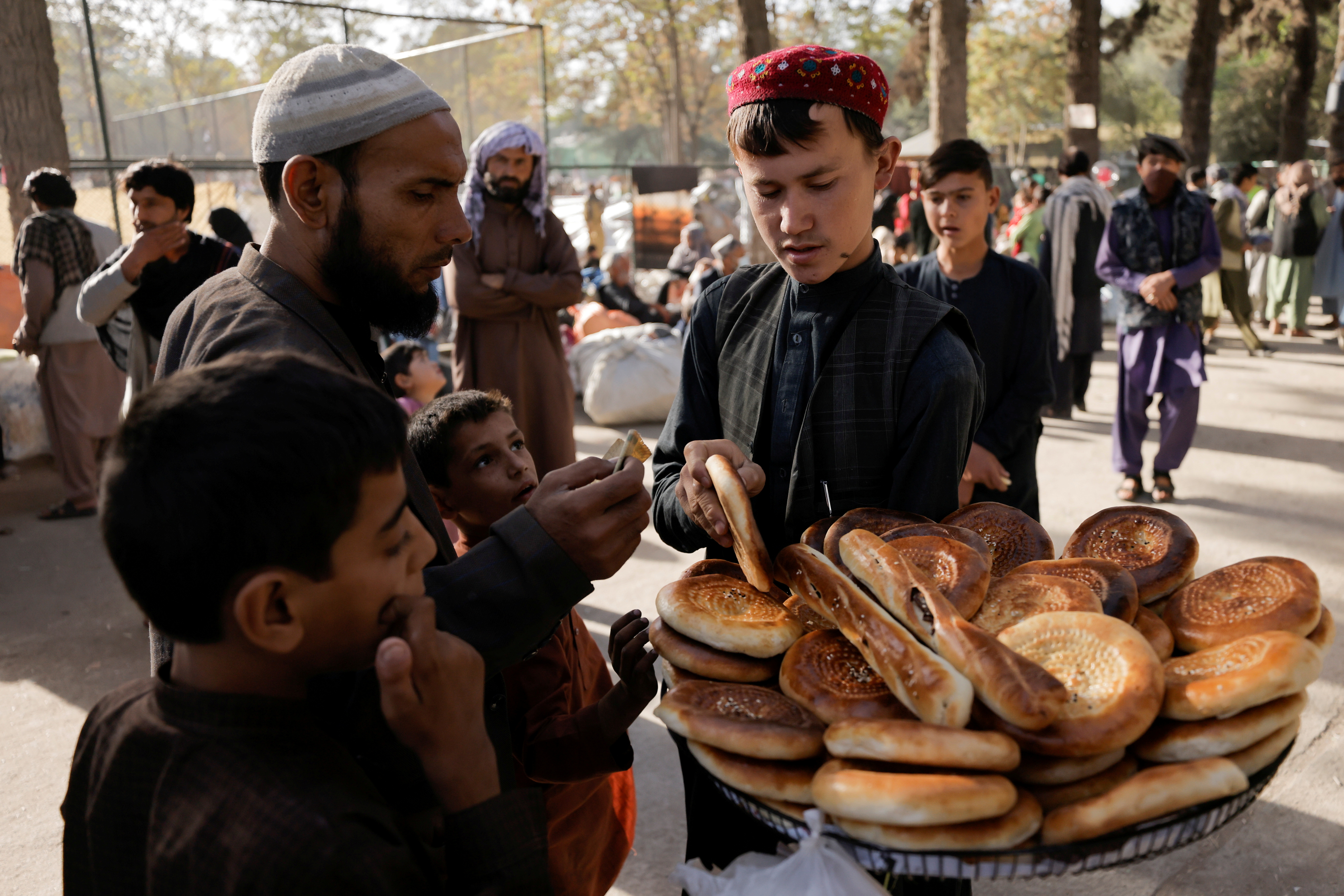 A boy sells bread at a makeshift shelter for displaced Afghan families, who are fleeing the violence in their provinces, at Shahr-e Naw park, in Kabul, Afghanistan, on Sunday. International officials are preparing to fly in cash for the needy while avoiding financing the Taliban government, according to people familiar with the confidential plans.