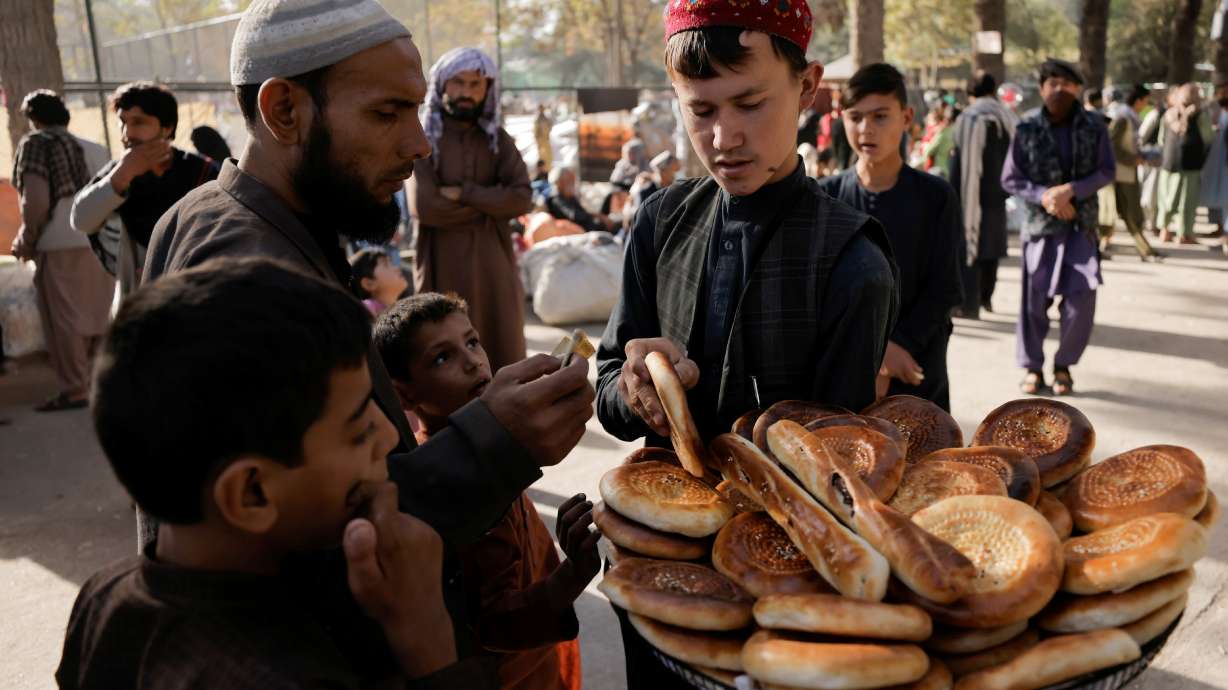 A boy sells bread at a makeshift shelter for displaced Afghan families, who are fleeing the violence in their provinces, at Shahr-e Naw park, in Kabul, Afghanistan, on Sunday. International officials are preparing to fly in cash for the needy while avoiding financing the Taliban government, according to people familiar with the confidential plans.