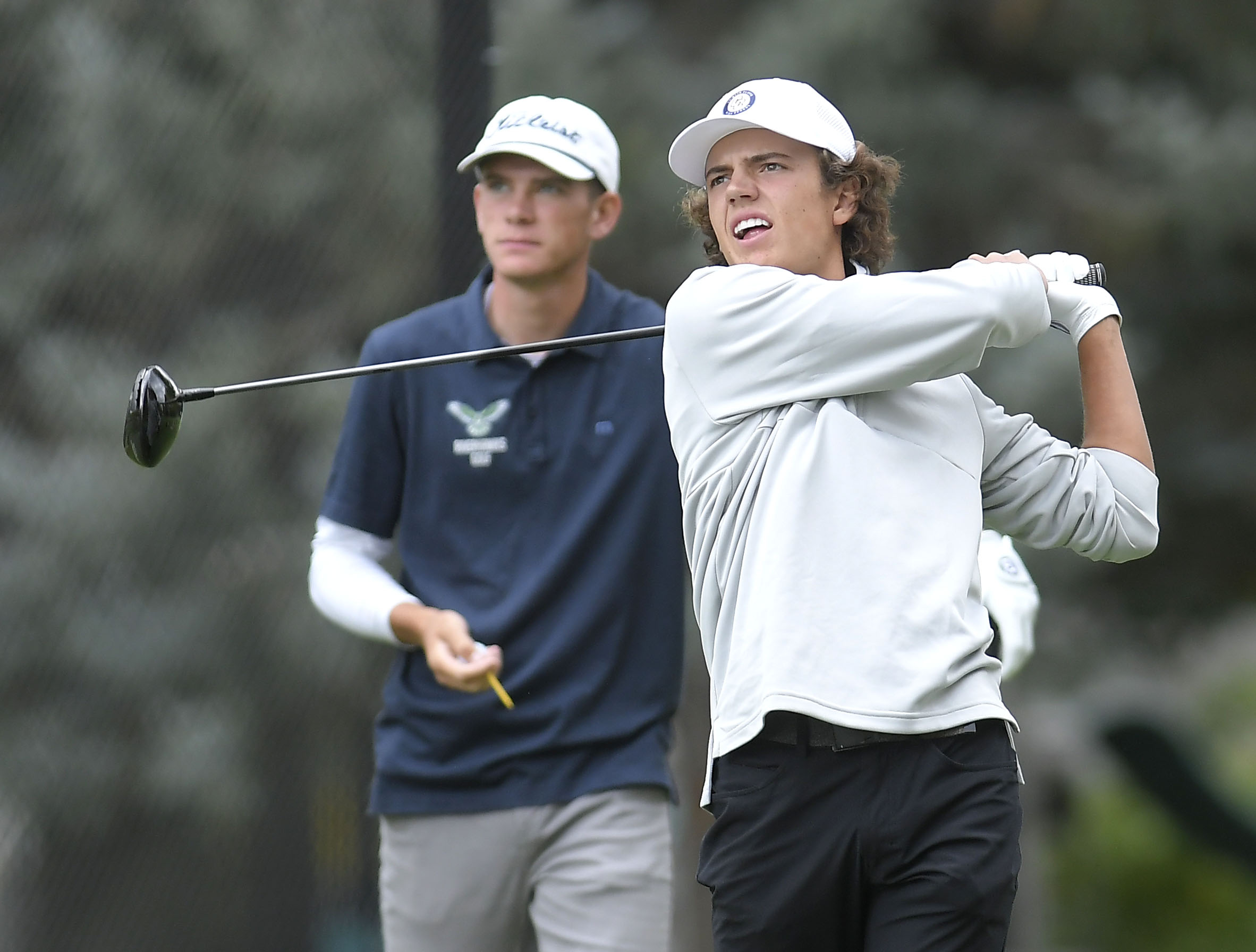 Ridgeline High School's Zach Skinner, left, watches as Crimson Cliffs High School's Boston Bracken hits his tee shot on the fourth hole at Birch Creek Golf CourseĀ during the first round of the 4A boys state championships in Smithfield on Wednesday, Oct. 6, 2021.