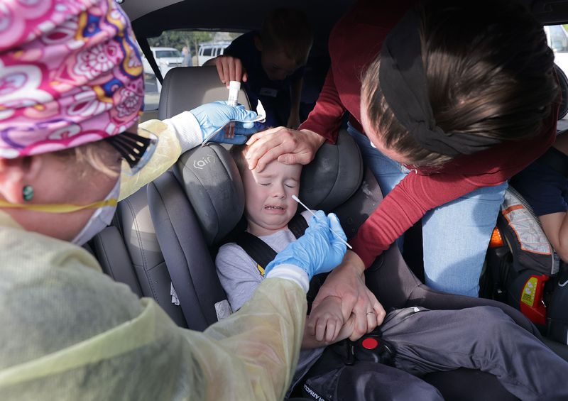 Melyn Henderson holds her son as he is tested for COVID-19 by Tiffanie Tabor at Cottonwood Heights City Hall parking lot on Sept. 30. Utah health officials confirmed 2,340 new COVID-19 cases and 12 deaths on Thursday. 