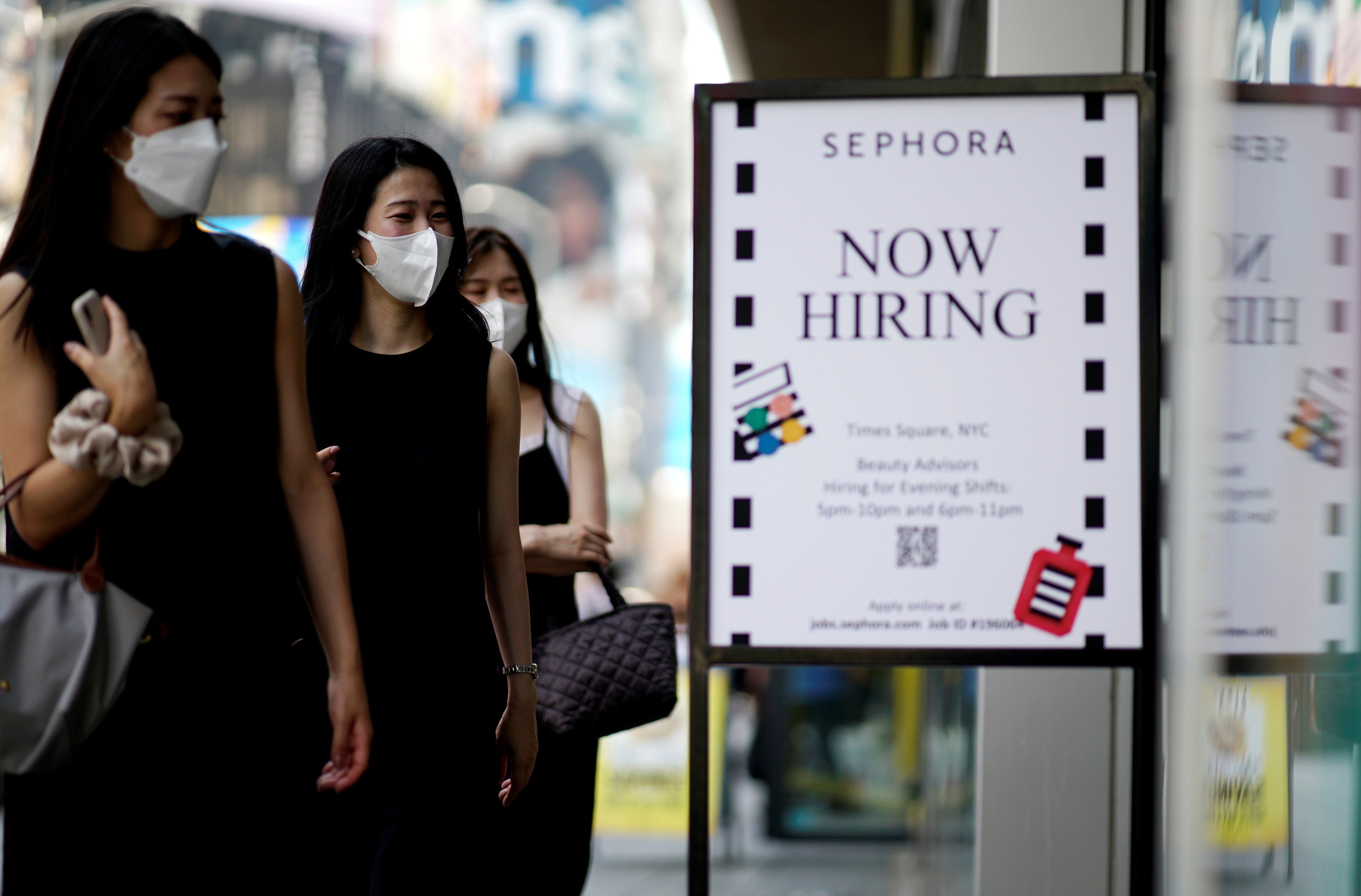 A sign advertising job openings is seen while people walk into the store in New York City, New York, U.S., August 6, 2021. U.S. employment increased far less than expected in September amid a decline in government payrolls, but hiring could pick up in the months ahead as COVID-19 infections subside and people resume the search for work.