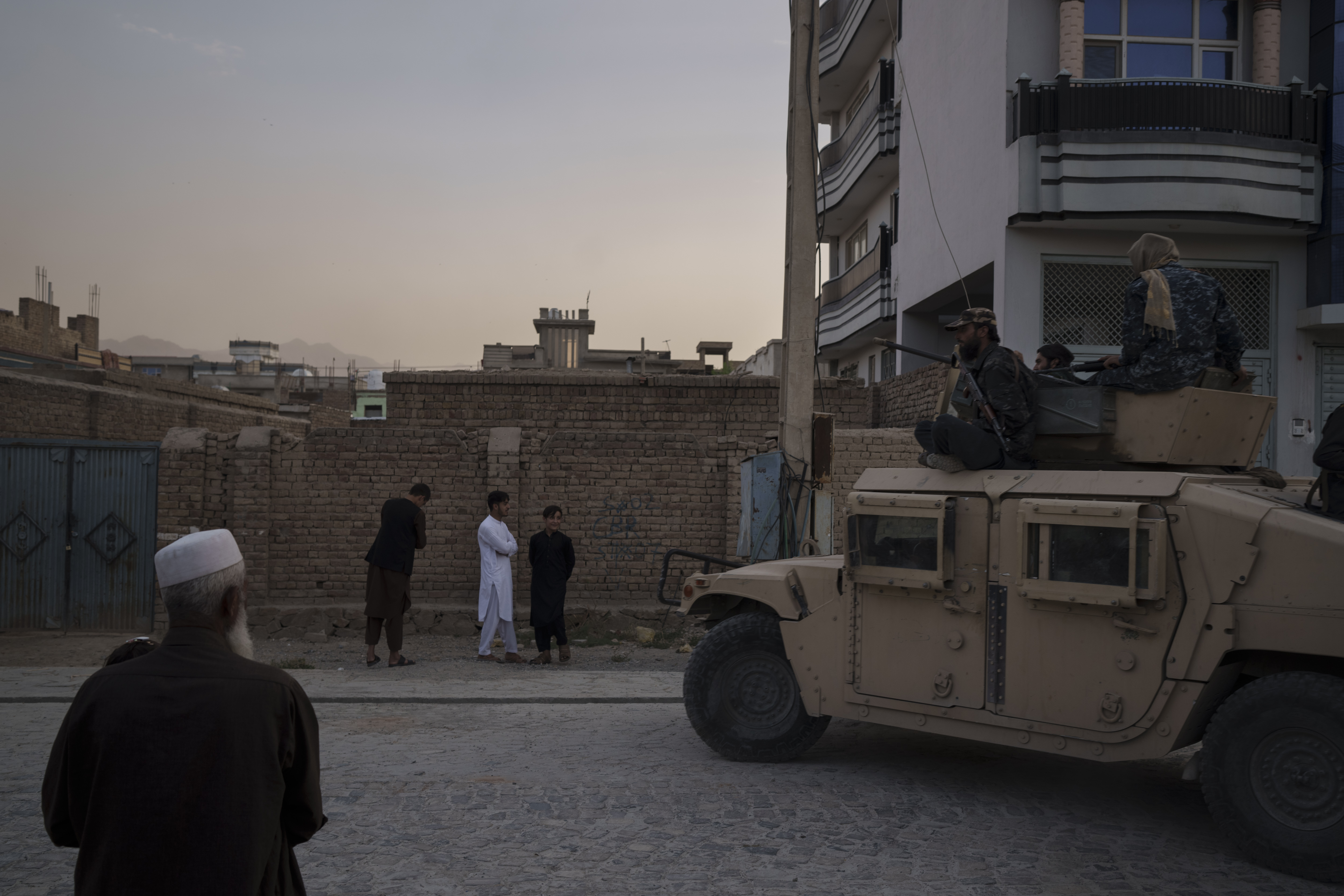 Afghans watch as Taliban fighters ride atop a humvee after detaining four men who got involved in a street fight in Kabul, Afghanistan, on Sept. 21.
