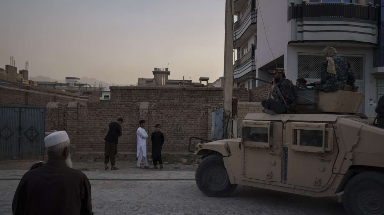 Afghans watch as Taliban fighters ride atop a humvee after detaining four men who got involved in a street fight in Kabul, Afghanistan, on Sept. 21.