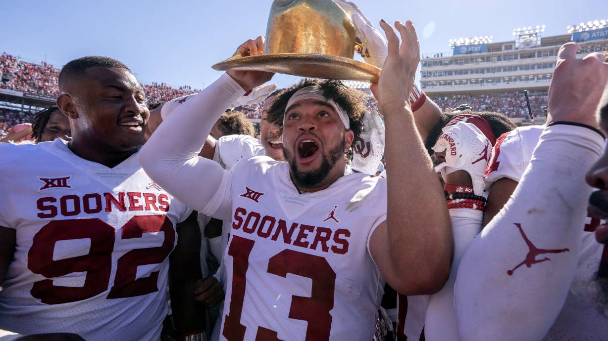 Oklahoma quarterback Caleb Williams (13) puts on the Golden Hat after coming off the bench to lead Oklahoma to a 54-48 win over Texas in an NCAA college football game at the Cotton Bowl, Saturday, Oct. 9, 2021, in Dallas.