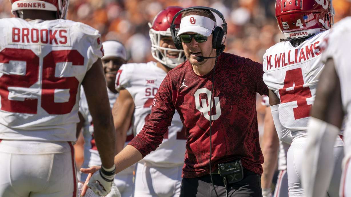 Oklahoma head coach Lincoln Riley congratulates running back Kennedy Brooks (26) and other players during the fourth quarter of an NCAA college football game against Texas at the Cotton Bowl, Saturday, Oct. 9, 2021, in Dallas. Oklahoma won 54-48.