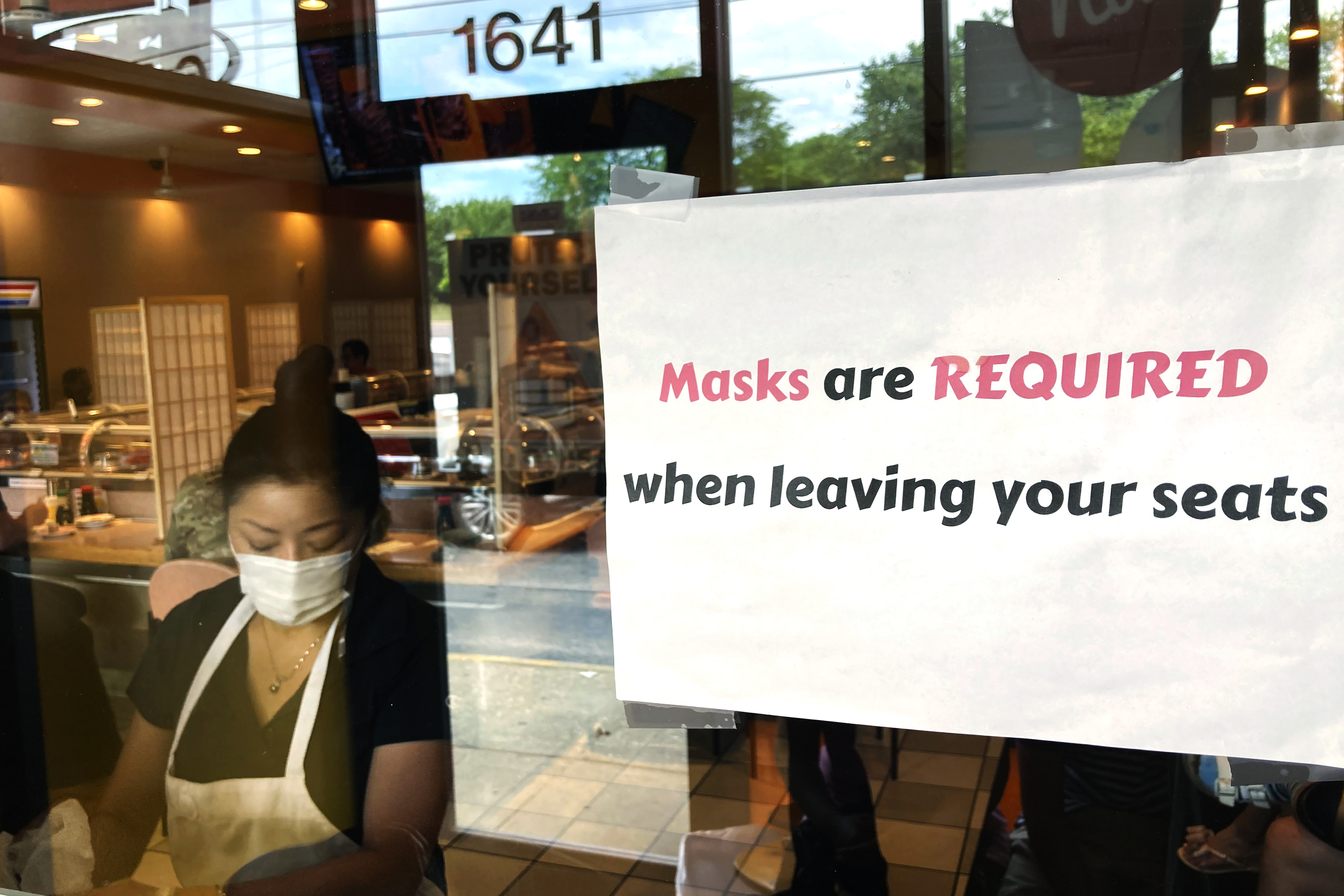 In this June 17, photo a sign requiring masks is displayed at a restaurant in Rolling Meadows, Illinois. 