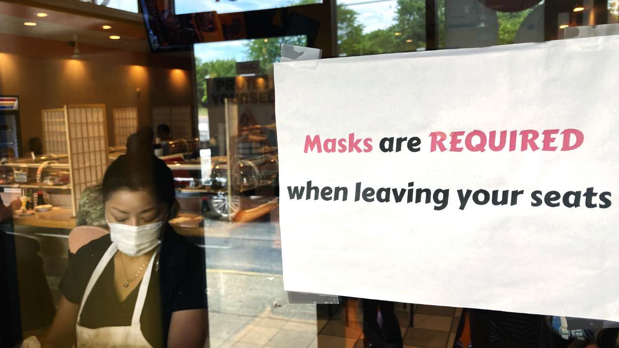 In this June 17, photo a sign requiring masks is displayed at a restaurant in Rolling Meadows, Illinois.