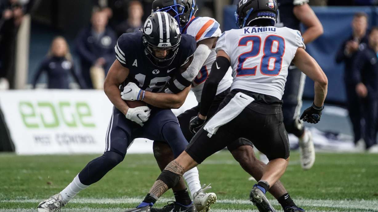 BYU wide receiver Gunner Romney (18) gets pressed by Boise State cornerback Caleb Biggers as Kekaula Kaniho watches during an NCAA college football game at LaVell Edwards Stadium in Provo on Saturday, Oct. 9, 2021.