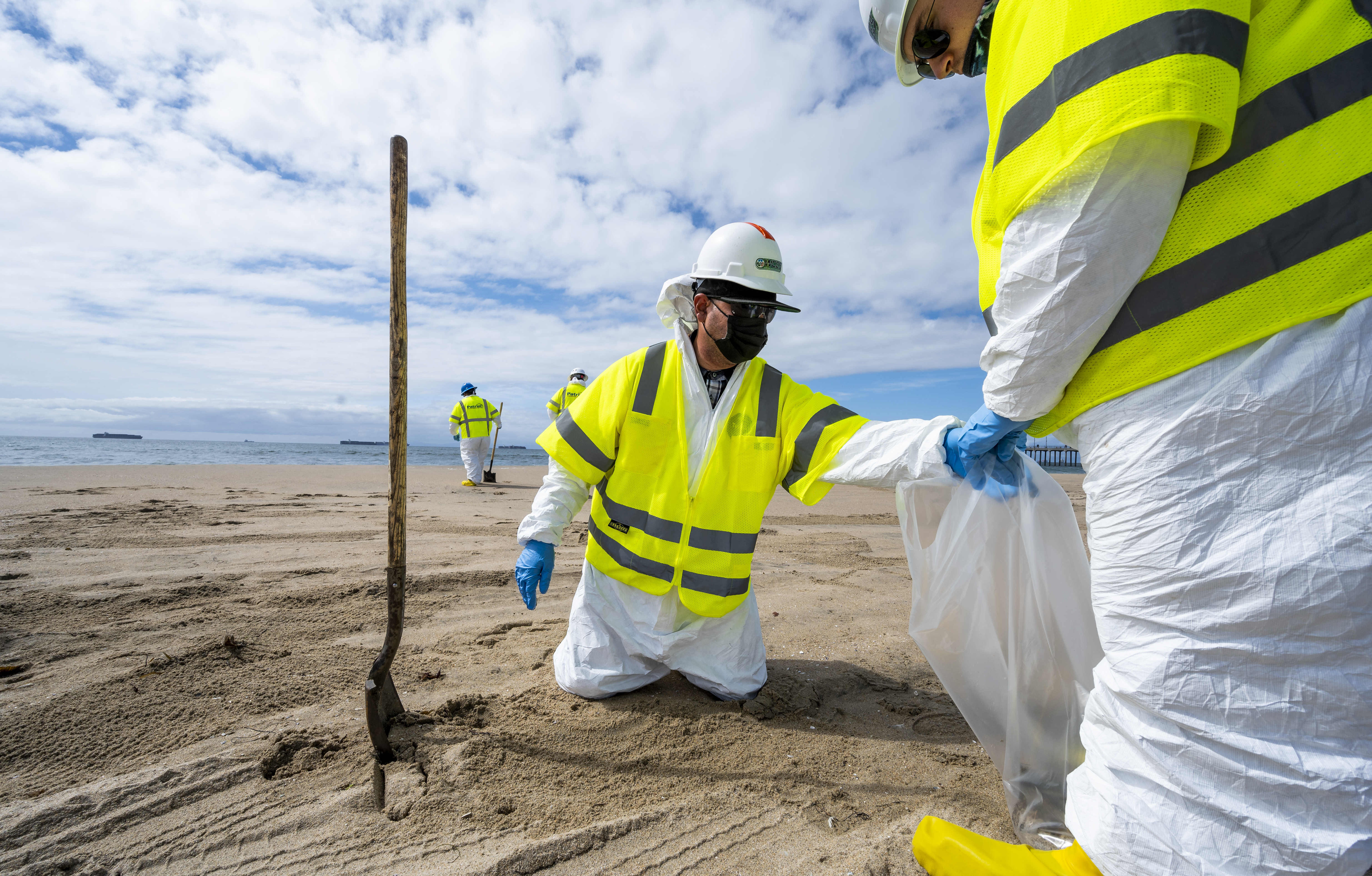 Workers with Patriot Environmental Services pick through the sand looking for pieces of oil south of the pier in Huntington Beach, Calif., on Friday. 