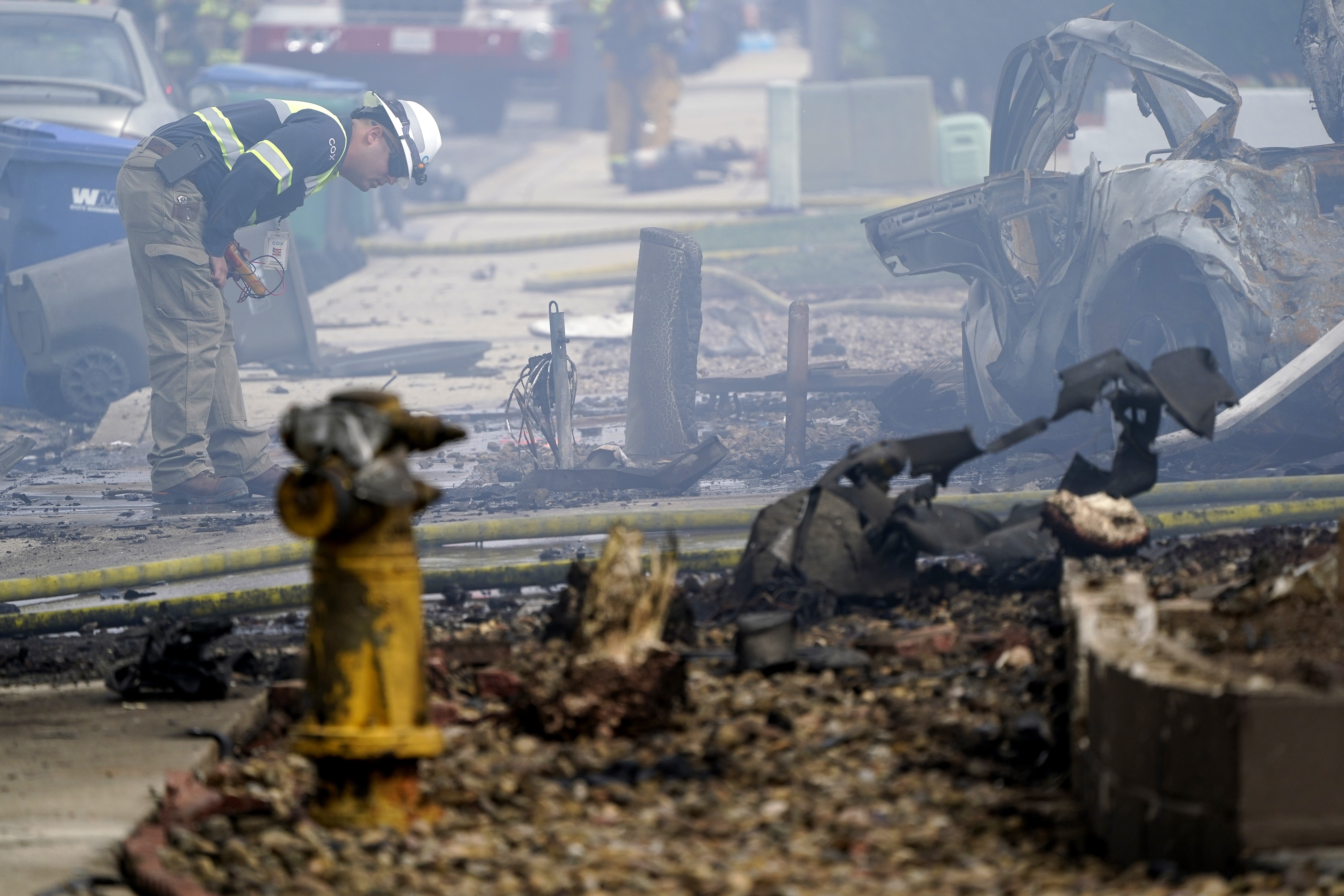 A fire official looks over the scene of a small plane crash, Monday, in Santee, Calif. At least two people were killed and two others were injured when the plane crashed into a suburban Southern California neighborhood, setting two homes ablaze, authorities said. 